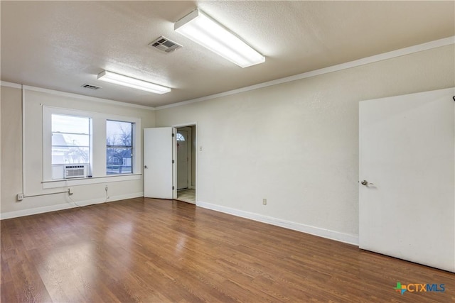 empty room featuring a textured ceiling, wood finished floors, and visible vents