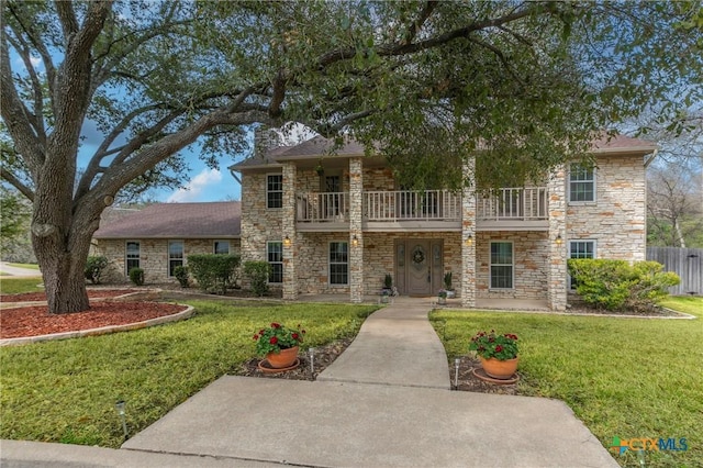 view of front of property with a balcony, a chimney, fence, and a front yard