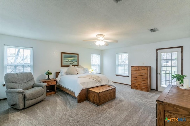 bedroom with access to exterior, visible vents, light colored carpet, ceiling fan, and a textured ceiling