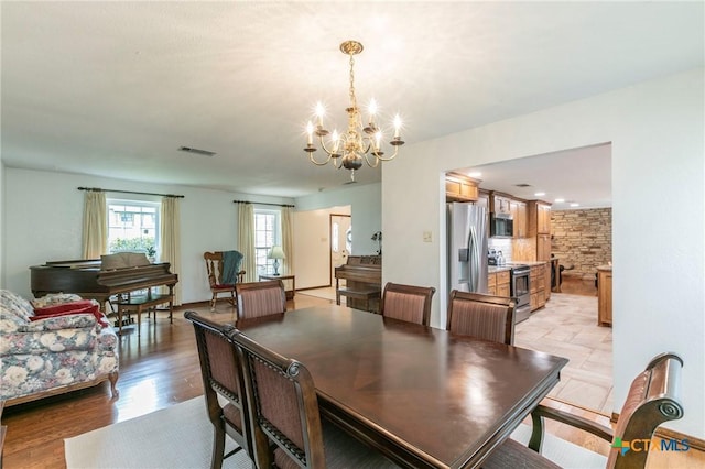 dining space featuring light wood finished floors, visible vents, and a chandelier