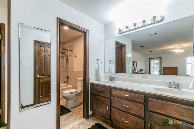 bathroom featuring toilet, double vanity, washtub / shower combination, and a sink