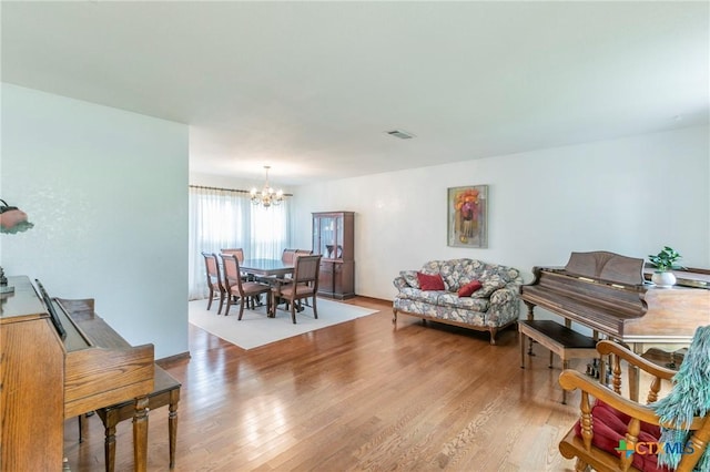 living area with an inviting chandelier, visible vents, and wood finished floors