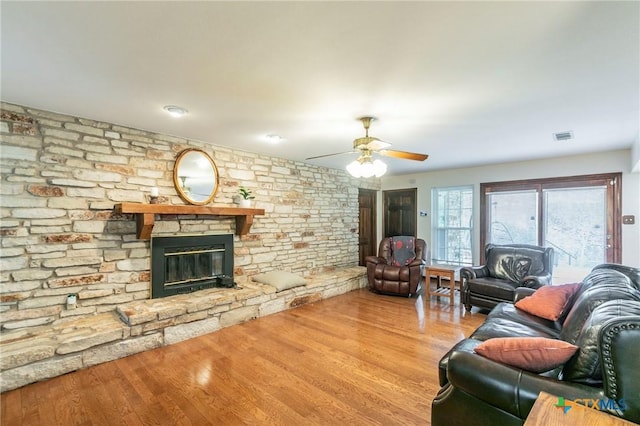 living area featuring ceiling fan, visible vents, a fireplace, and wood finished floors