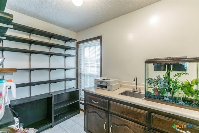 interior space with open shelves, light countertops, light tile patterned flooring, a sink, and a textured ceiling