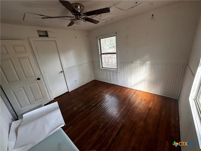 spare room with ceiling fan, wood walls, and dark hardwood / wood-style flooring