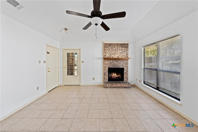 unfurnished living room featuring a brick fireplace, ceiling fan, light tile patterned floors, and vaulted ceiling