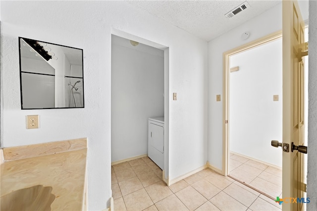 bathroom with tile patterned floors, washer / dryer, and a textured ceiling