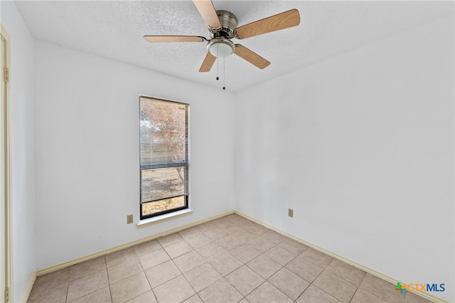 tiled empty room with ceiling fan, a healthy amount of sunlight, and a textured ceiling