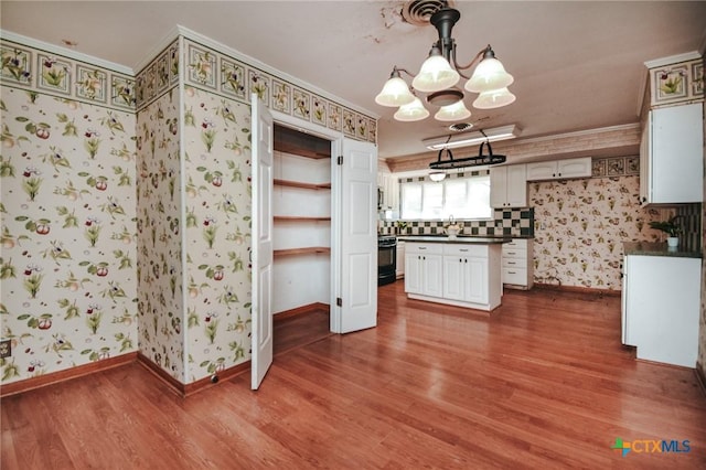 kitchen featuring white cabinets, hardwood / wood-style flooring, ornamental molding, and decorative light fixtures