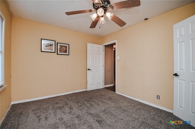 unfurnished bedroom with ceiling fan, dark carpet, and a textured ceiling