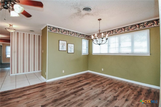 unfurnished dining area with hardwood / wood-style flooring, ceiling fan with notable chandelier, ornamental molding, and a textured ceiling