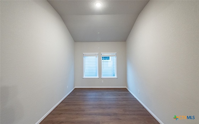 unfurnished room with dark wood-type flooring and lofted ceiling