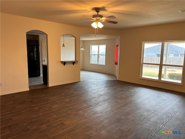 empty room with a textured ceiling, dark wood-type flooring, and ceiling fan