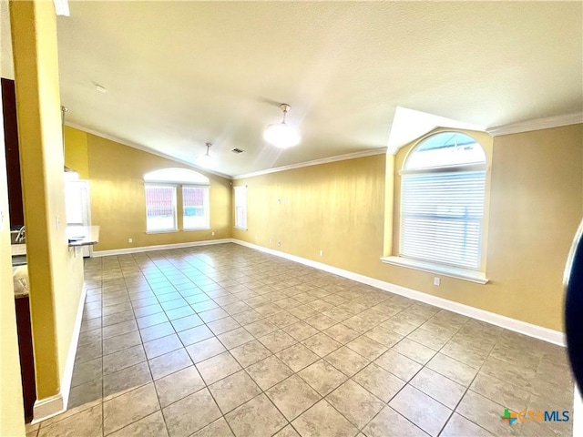 empty room featuring vaulted ceiling, light tile patterned flooring, crown molding, and baseboards