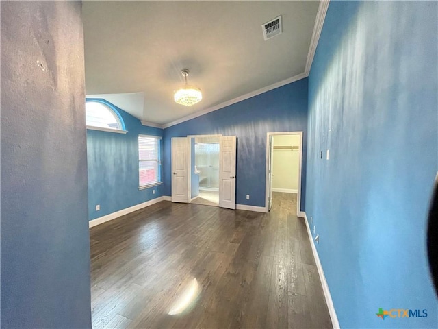 spare room featuring lofted ceiling, ornamental molding, wood finished floors, and visible vents