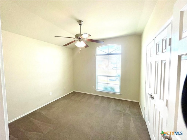 unfurnished bedroom with a ceiling fan, vaulted ceiling, dark carpet, and baseboards