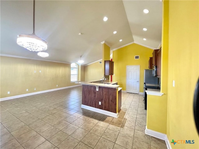 kitchen with lofted ceiling, a kitchen breakfast bar, open floor plan, light countertops, and ornamental molding