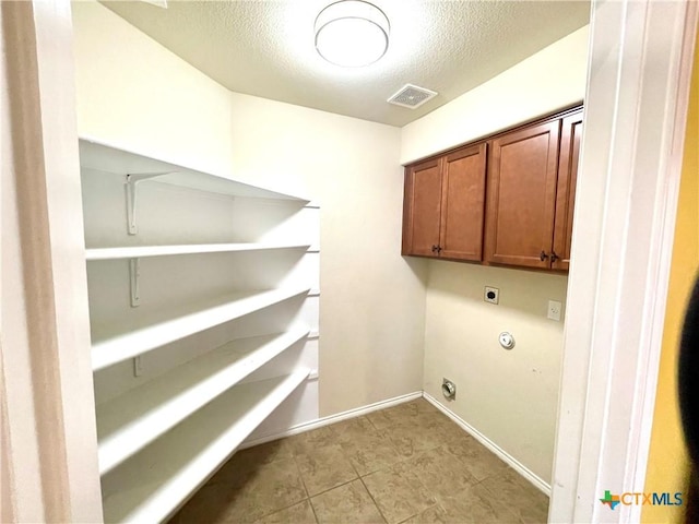 laundry area with a textured ceiling, visible vents, baseboards, cabinet space, and electric dryer hookup