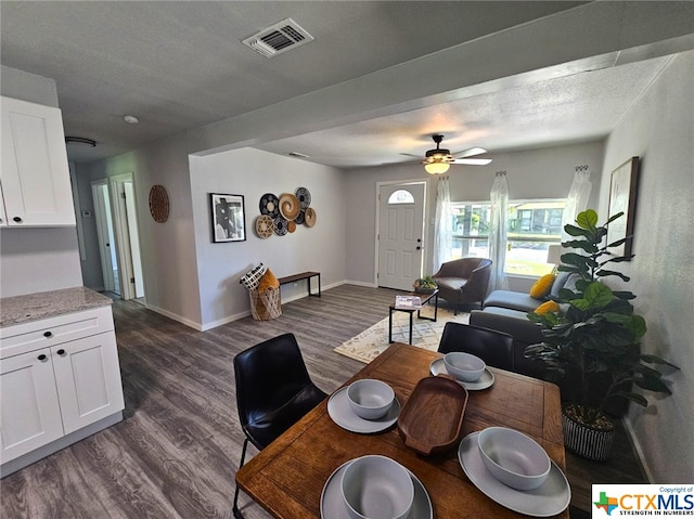 living room with a textured ceiling, ceiling fan, and dark wood-type flooring