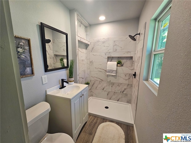 bathroom featuring tiled shower, hardwood / wood-style floors, vanity, and toilet