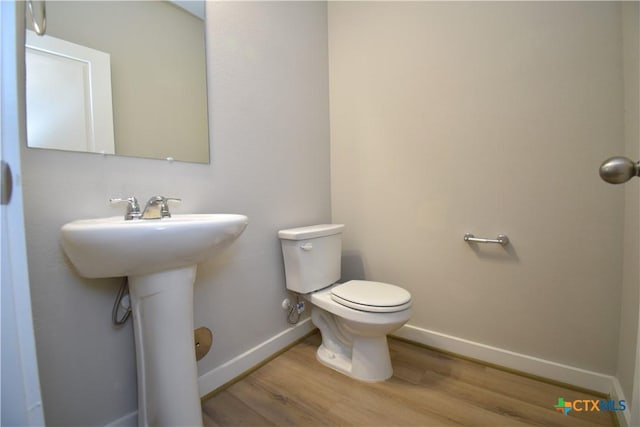 bathroom featuring a sink, wood finished floors, toilet, and baseboards