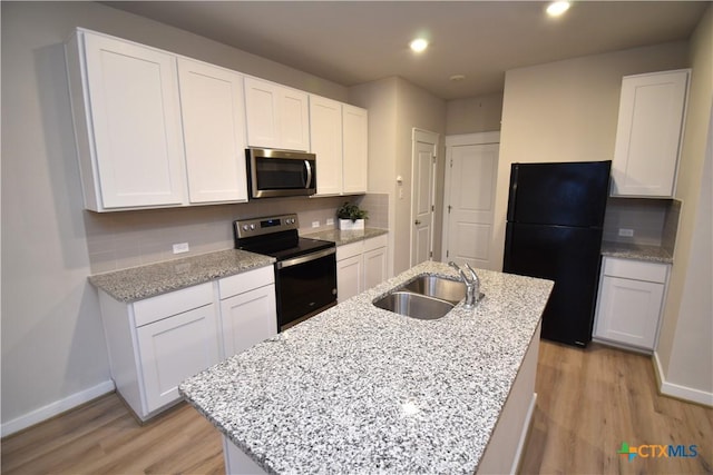 kitchen with a sink, white cabinets, freestanding refrigerator, electric range oven, and stainless steel microwave