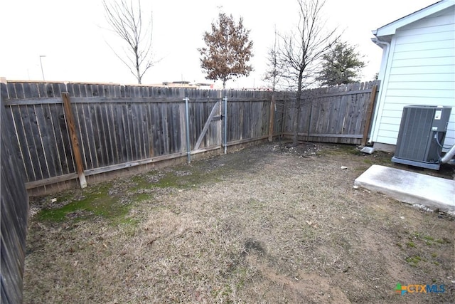 view of yard with a fenced backyard and central AC unit