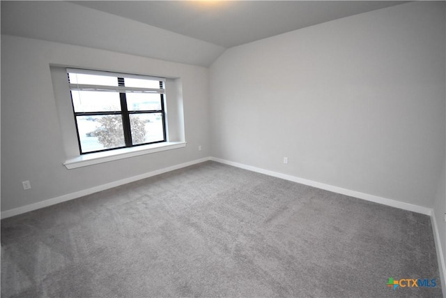 unfurnished room with lofted ceiling, baseboards, and dark carpet