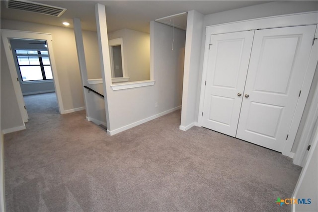 interior space with visible vents, light carpet, attic access, and baseboards