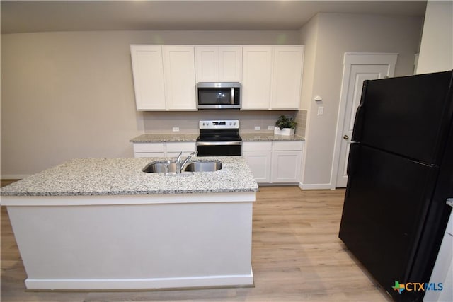 kitchen featuring appliances with stainless steel finishes, a kitchen island with sink, white cabinets, a sink, and light stone countertops