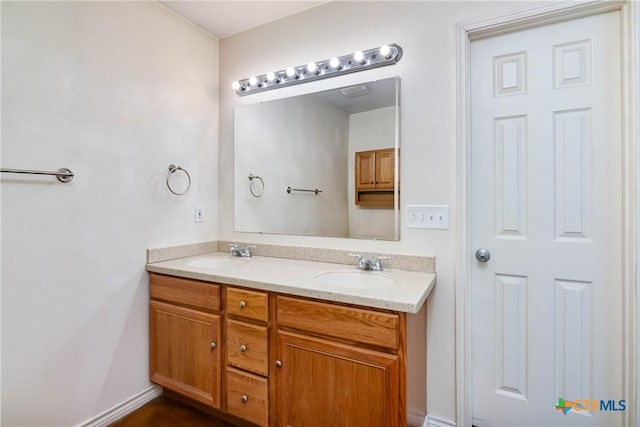 bathroom with double vanity, baseboards, and a sink