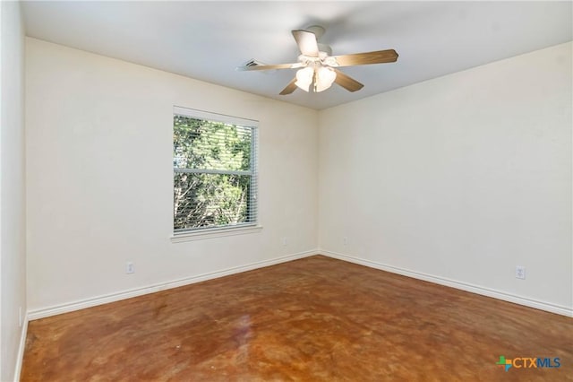 spare room featuring ceiling fan, concrete floors, and baseboards