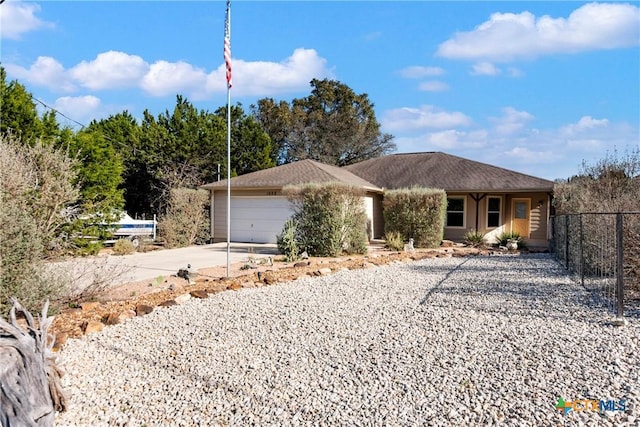 ranch-style home with driveway, an attached garage, and fence