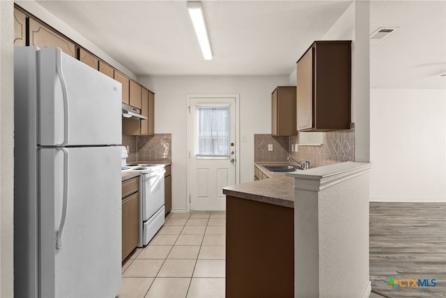 kitchen with decorative backsplash, light hardwood / wood-style flooring, white appliances, and sink