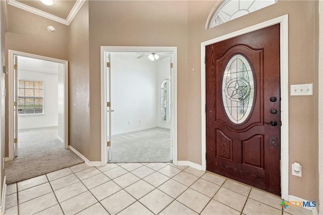 foyer featuring ornamental molding, light carpet, baseboards, and light tile patterned floors