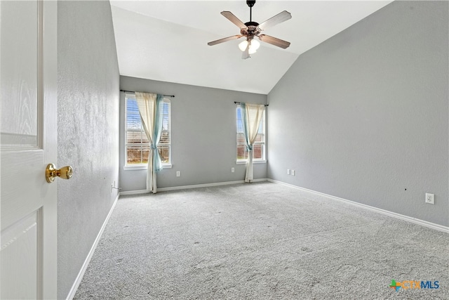 spare room featuring lofted ceiling, carpet flooring, a ceiling fan, and baseboards