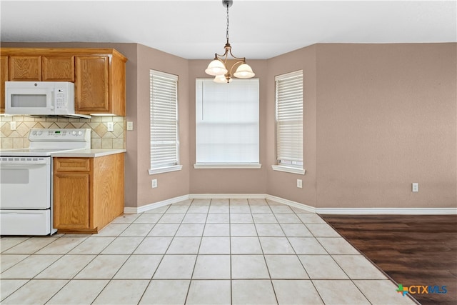 kitchen featuring a notable chandelier, white appliances, baseboards, light countertops, and backsplash