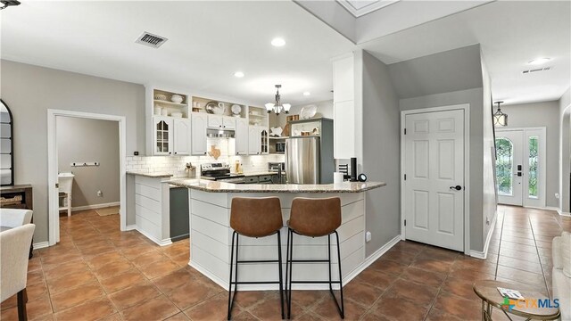 405 Pinnacle Pkwy, New Braunfels, TX 78132 - kitchen featuring stainless steel appliances, tasteful backsplash, glass insert cabinets, a peninsula, and a chandelier