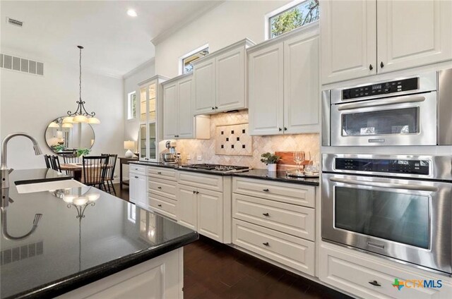 124 Schooner Dr, Lakeway, TX 78738 - kitchen featuring dark countertops, decorative backsplash, stainless steel appliances, white cabinetry, and hanging light fixtures