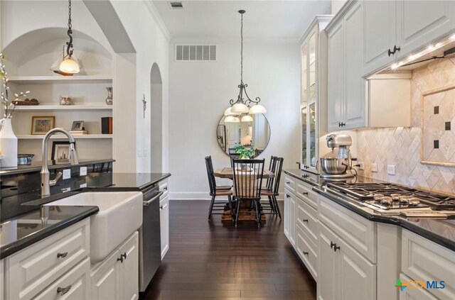 124 Schooner Dr, Lakeway, TX 78738 - kitchen with dark countertops, appliances with stainless steel finishes, white cabinets, dark wood finished floors, and arched walkways