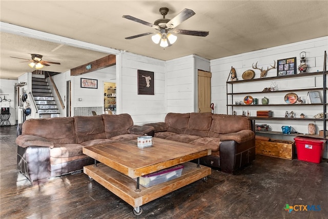 living room featuring dark wood-type flooring, wooden walls, a textured ceiling, and ceiling fan