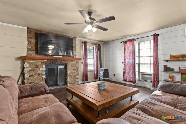 living room with a fireplace, wood walls, and ceiling fan