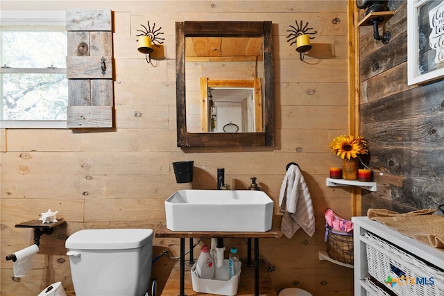 bathroom featuring wood walls, sink, and toilet