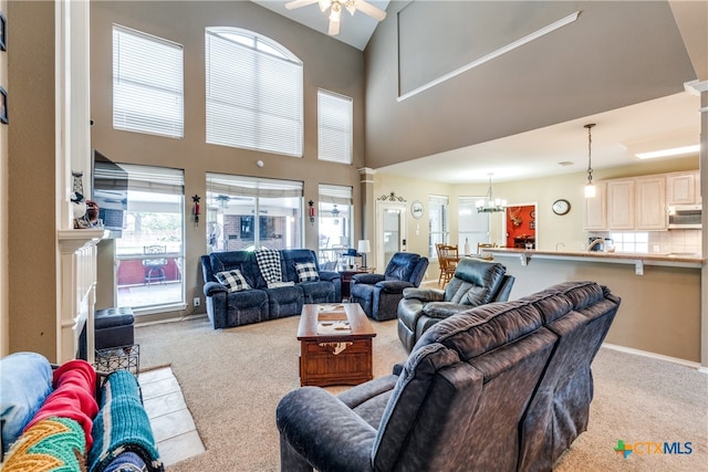 living room featuring ceiling fan with notable chandelier, plenty of natural light, and light carpet