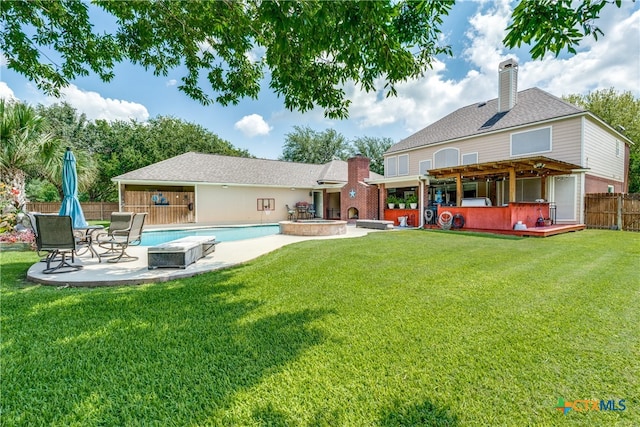 back of property featuring a swimming pool with hot tub, a lawn, and a patio