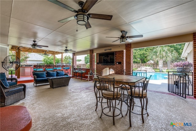 view of patio / terrace featuring ceiling fan, a fenced in pool, and an outdoor living space with a fireplace