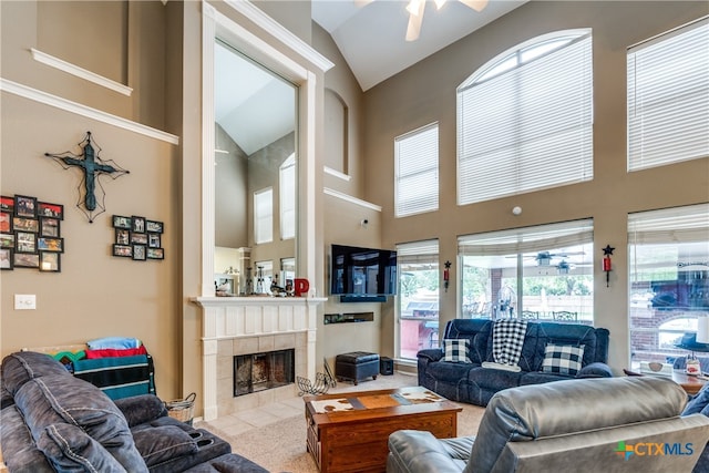 living room featuring high vaulted ceiling, light colored carpet, ceiling fan, and a tile fireplace