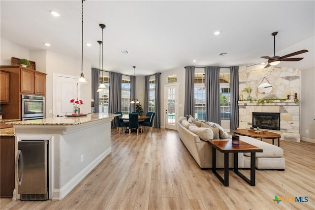 living room featuring ceiling fan, light wood-style flooring, and beverage cooler