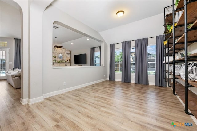 spare room with arched walkways, a ceiling fan, wood finished floors, and vaulted ceiling