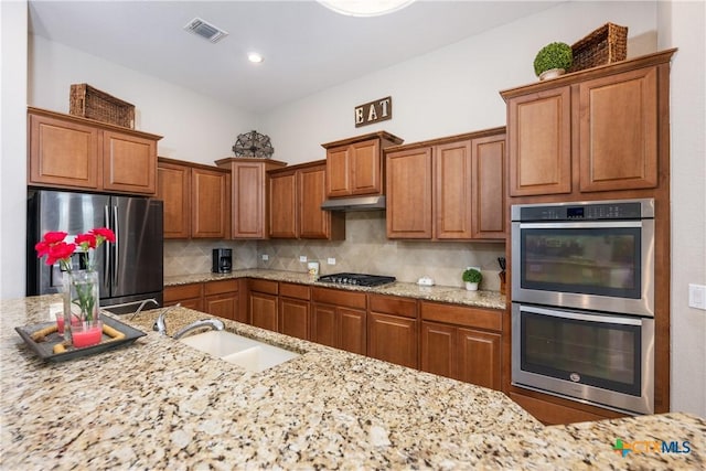kitchen featuring brown cabinets, visible vents, stainless steel appliances, and a sink